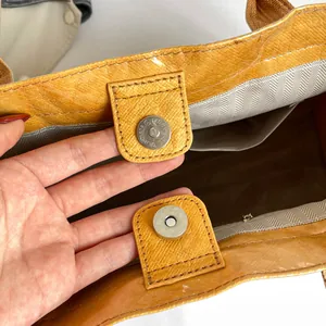 Primer plano del cierre magnético y forro de espiga del bolso tote amarillo