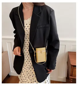 Model wearing a gold acrylic box bag with beaded chain strap over a black blazer.