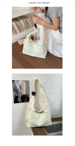 Detail view of a cream minimalist shoulder tote bag with blue zipper accents