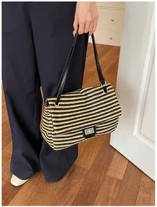 Detalle de un elegante bolso de hombro de paja trenzada con rayas negras y beige claro