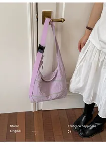 Detailed view of a lilac purple minimalist women's shoulder bag hanging on a white door handle
