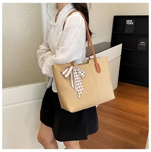 Model met een beige shopper, bruine handvatten en decoratieve zijden sjaal detail