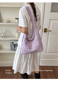 Minimalist purple nylon hobo shoulder bag styled on a model in a clean studio setting