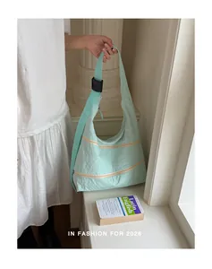 Detail view of light blue nylon bag with multiple zippers and adjustable shoulder strap