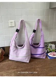 Close-up of two retro purple nylon shoulder bags with dual front zippers in a casual setting