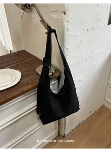 Minimalist black crescent hobo bag hanging on a vintage desk lamp in a home setting