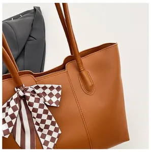 Detail van een grote bruine kunstlederen shopper met een geruite zijden sjaal decor