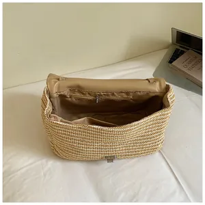 Primer plano del espacioso compartimento interior con bolsillo de cremallera en bolso de paja.