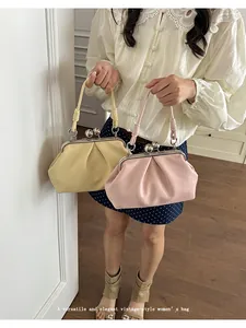 Close-up view of vintage-style pleated cloud kiss-lock handbags in yellow and pink