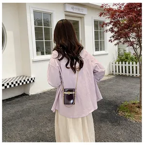 Back view of a model wearing a dark purple transparent acrylic box bag with gold chain