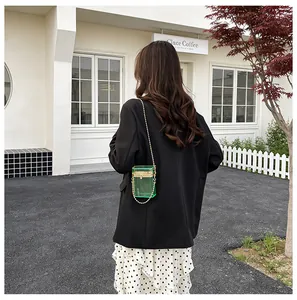 Back view of model wearing a stylish green transparent acrylic box bag with gold chain