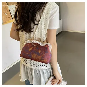 Detalle de bolso chino vintage con encaje y una elegante correa de perlas para el hombro.