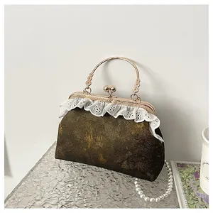 Elegante bolso vintage con detalles de encaje y asa dorada sobre una base de plata.