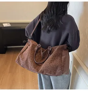 Model wearing a large leopard print travel bag with shoulder strap in a stylish interior