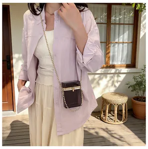 Close-up view of a stylish dark grey acrylic transparent box bag with a golden chain strap