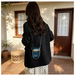Stylish blue acrylic transparent box bag with gold chain worn on a black blazer.