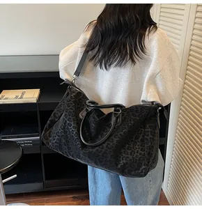 Large leopard print travel tote bag shown on model in a modern interior setting.
