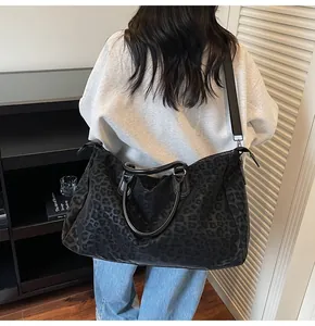 Stylish large black leopard print travel bag shown being worn as a crossbody on a model.