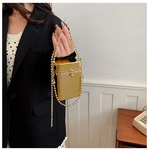 Elegant gold metallic box bag with beaded strap shown in a lifestyle setting