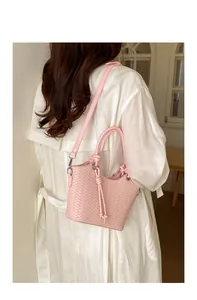 Elegante rosa geflochtene Beuteltasche kombiniert mit weißem Outfit im hellen Raum