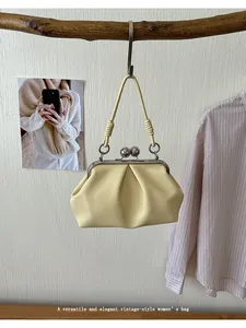 Detailed view of an elegant pleated cream handbag with a vintage silver metal clasp