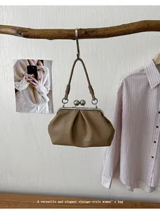 Vintage pleated cloud handbag hung on a rustic wooden branch detail view