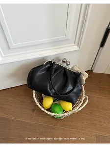 Black pleated cloud bag presented in a woven basket with fresh yellow lemons