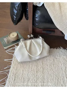 Detailed view of the pleated cream leather cloud bag with silver kiss-lock closure.