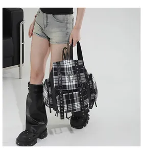 Detailansicht eines trendigen Karo-Rucksacks mit Metallnieten und Kreuzemblem Design.