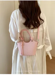 Detail einer rosa geflochtenen Eimertasche am Modell mit minimalistischem Retro-Design.