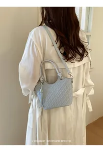 Hellblaue geflochtene Beuteltasche am Modell mit minimalistischem Retro-Vibe-Design.