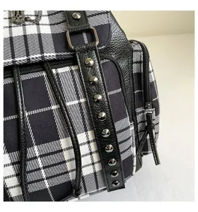 Detailaufnahme der schwarz-weiß karierten Tasche mit Metallnieten und Reißverschlüssen