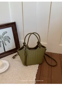 Detailansicht einer geflochtenen grünen Ledereimertasche mit Tragegriff und Gurt