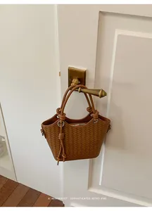 Braune gewebte Beuteltasche hängen an einem Vintage Messing Türgriff im Retro-Stil.