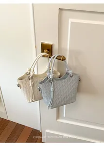 Zwei minimalistische gewebte Beuteltaschen in Creme und Hellblau an einem Türgriff.