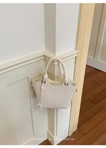 Nahaufnahme einer cremefarbenen geflochtenen Eimertasche mit geknotetem Riemendetail