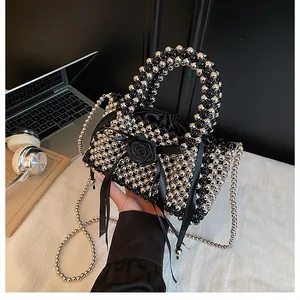 Primo piano di borsa a mano con perline nere e argento con decorazione rosa fatta a mano.