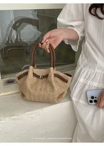 Detalle del elegante bolso de paja trenzada con asas de cuero marrón