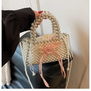 Dettaglio della borsa a secchiello in perle fatta a mano con rosa in seta rosa e tracolla.