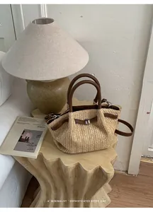 Elegante bolso de paja trenzada con detalles en cuero marrón y estilo retro