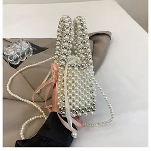 Dettaglio di un'elegante borsa a secchiello in perle acriliche e fiocco rosa
