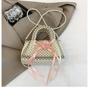 Dettaglio borsa di perle acriliche tessuta a mano con rosa rosa e fiocco di nastro.