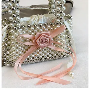 Primo piano di borsa a mano in perle fatta a mano con rosa in nastro rosa e fodera in raso.