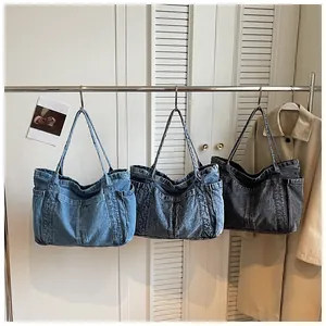 Vista detallada de tres bolsos tote de mezclilla informales colgados en tonos de azul