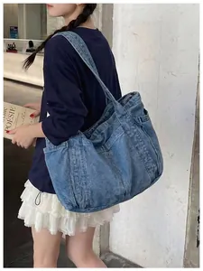 Vista detallada de un bolso de mano de mezclilla azul minimalista llevado por una modelo