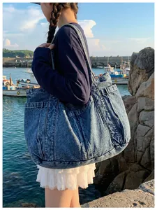 Bolso tote grande de mezclilla azul lavado llevado al hombro en un entorno costero natural