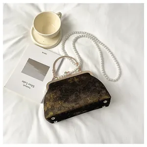 Vista detallada de un bolso vintage de estilo chino con textura metálica y perlas.