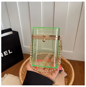 Close-up of a stylish lime green transparent acrylic box bag with a sleek gold chain strap.