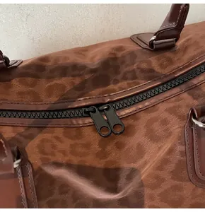 Detailed macro view showing the sturdy dual zipper on a stylish brown leopard print travel bag