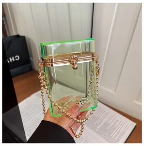 Detail of a transparent lime green acrylic box bag with a gold bead chain strap